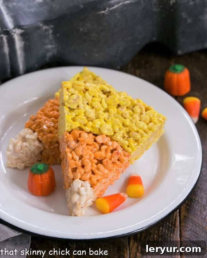 Candy Corn Rice Krispie Treats on round white plate, showcasing the distinct yellow, orange, and white layers.