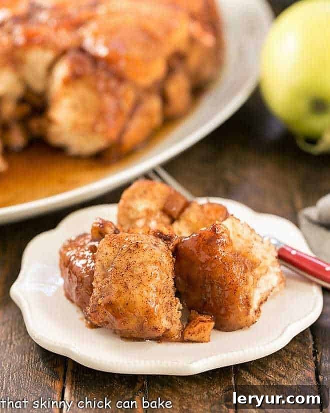 Golden brown apple monkey bread on a small white plate, ready to be served, showing its gooey caramel and apple pieces.