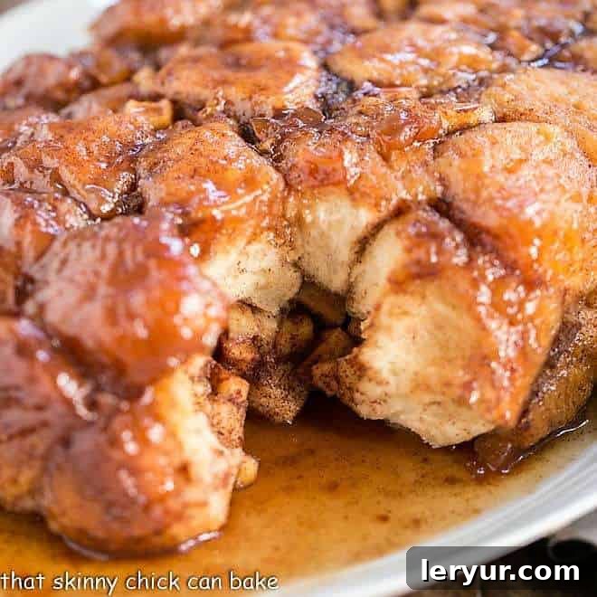 Apple Monkey Bread served on a large white serving platter, with individual pieces covered in caramel sauce.