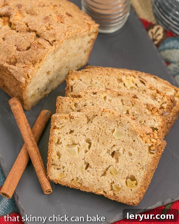 Two generous slices of Cinnamon Spiced Apple Bread and a partial loaf on a textured slate tray, showcasing the golden crust and soft interior.