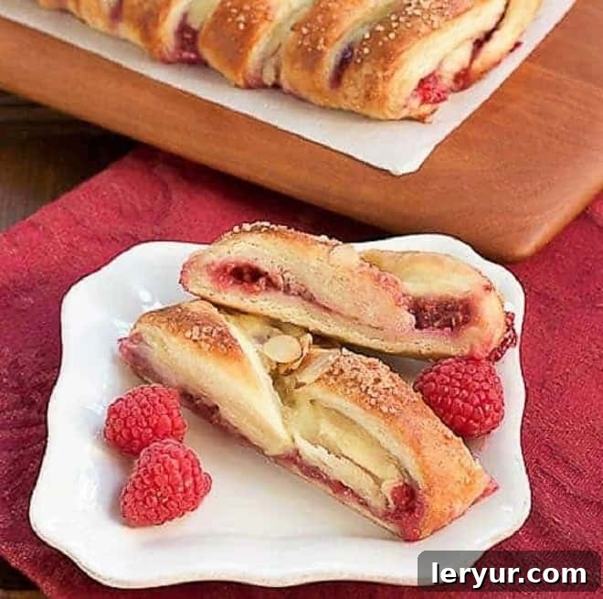 Raspberry Danish Braid slices on a white ceramic plate, ready to be served and enjoyed, showcasing its flaky layers and rich filling.