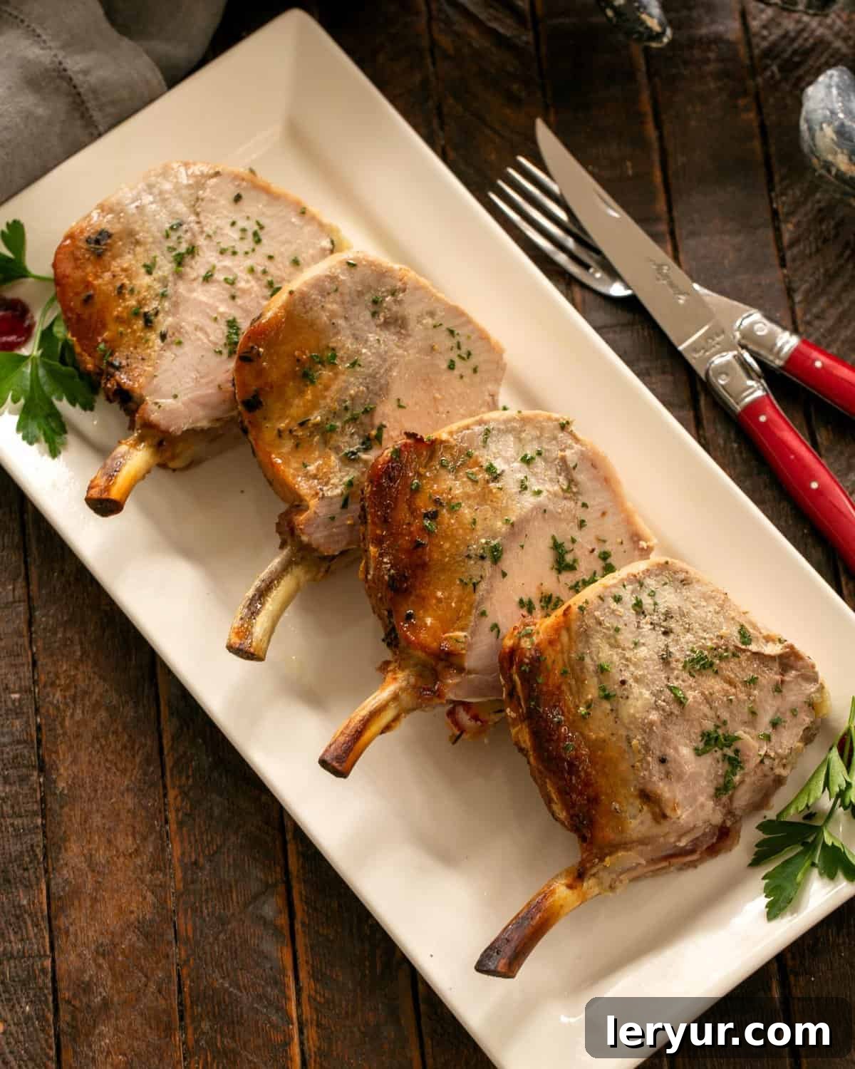 Regal Pork Crown with Spiced Apple Filling 3 A majestic sliced Crown Roast of Pork, beautifully garnished with fresh parsley, presented on a pristine white ceramic platter, ready to impress at a festive gathering.