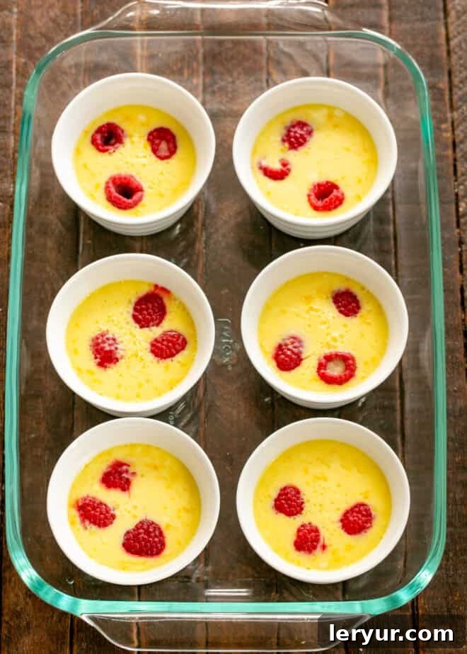 Ramekins baking in a water bath inside an oven, with the lemon mousse mixture visibly setting.