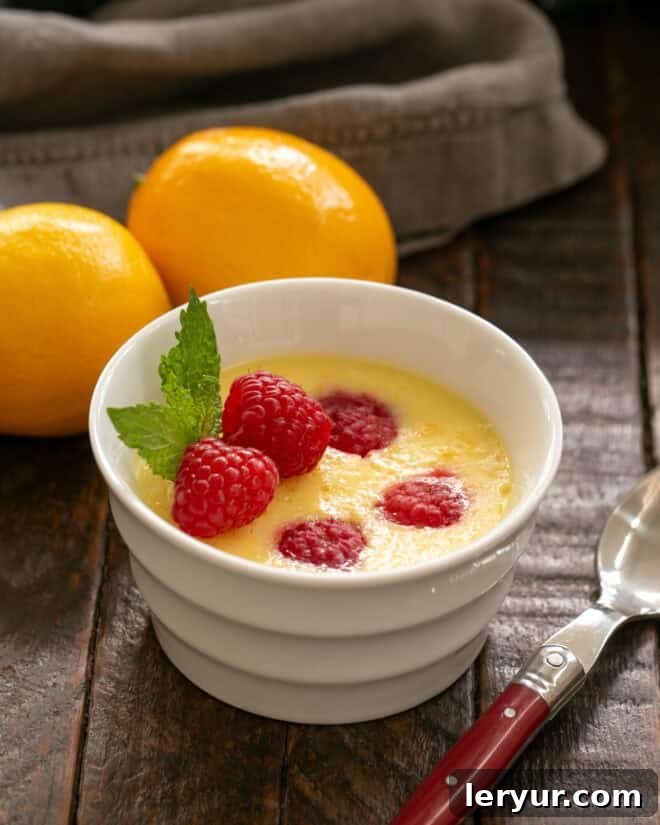 A finished Meyer Lemon Mousse, perfectly baked in a white ramekin, with a red-handled spoon resting beside it, ready to be enjoyed.