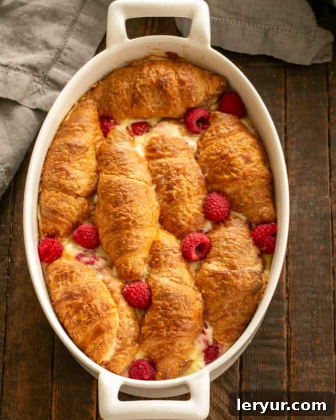 Decadent Croissant French Toast with Juicy Raspberries 9 Step 6: Baked croissant French toast casserole, garnished with powdered sugar and raspberries, ready to serve.