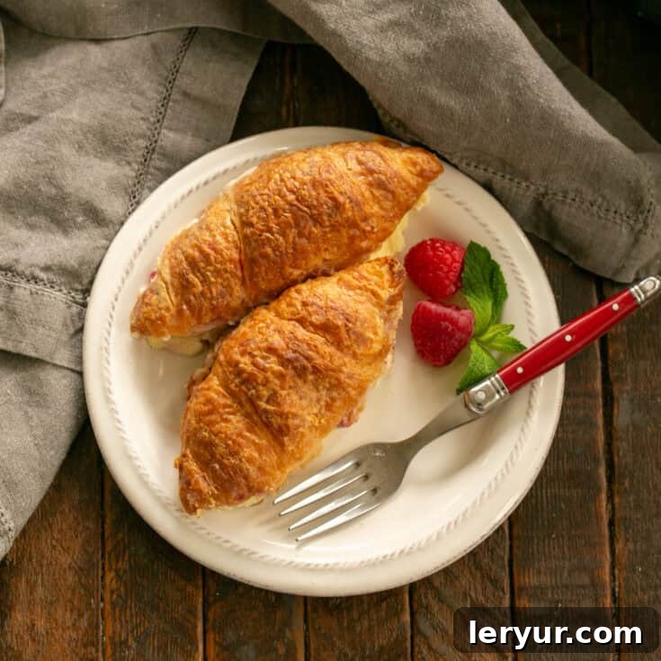 Overhead view of Croissant French Toast on a white plate with a berry garnish, ready to be enjoyed.