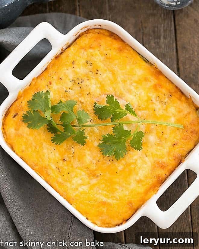 A square white baking dish filled with the golden, bubbling goodness of Chili Relleno Casserole, straight from the oven.