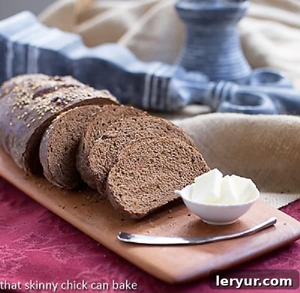 Rich, delicious Pumpernickel Loaves make a tasty breakfast, sandwich or dinner side! Sliced Pumpernickel loaves on a rustic cutting board, showcasing their rich texture