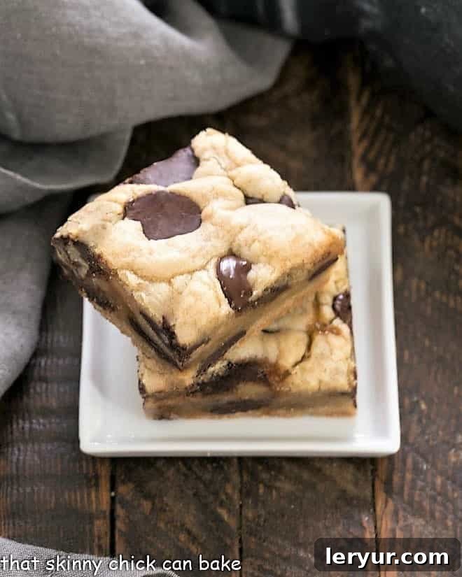 Chocolate Chip Cookie Bars with Caramel - an exquisite combination that's super easy to make! Two caramel chocolat chip bars stacked on a small square white plate.