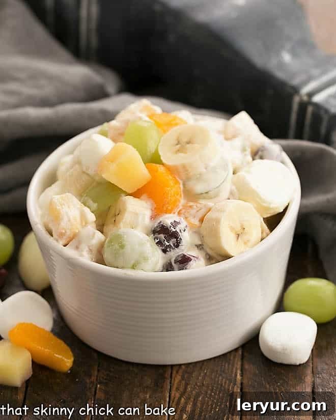Holiday Fruit Salad with Marshmallows - A salad that's been in our family for 4 generations! A beautifully presented 24-hour fruit salad in a white bowl, garnished with fresh fruit and marshmallows, ready for a festive occasion.