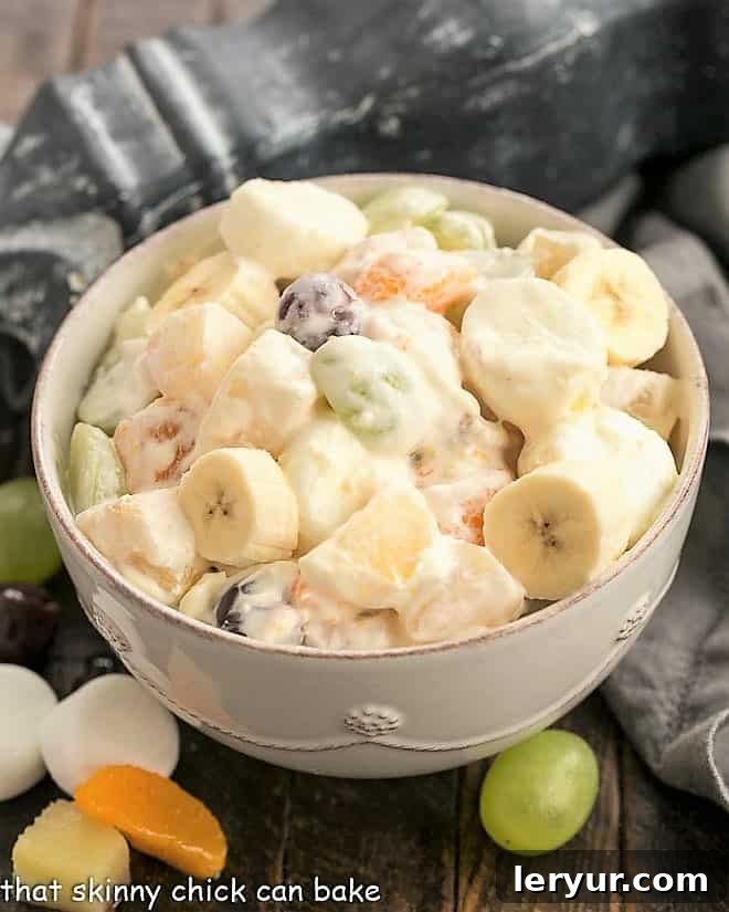 Holiday Fruit Salad with Marshmallows - A salad that's been in our family for 4 generations! A large white serving bowl filled with the completed Holiday Fruit Salad, garnished beautifully and ready to be served.