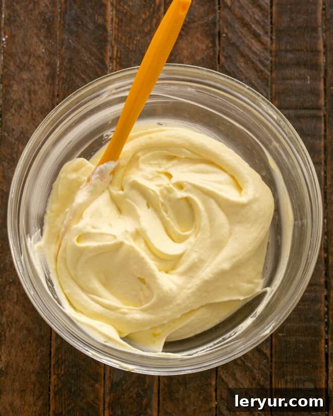 Holiday Ambrosia Salad 5 Gently mixing the lemon custard into the whipped cream until fully combined, creating a smooth dressing.