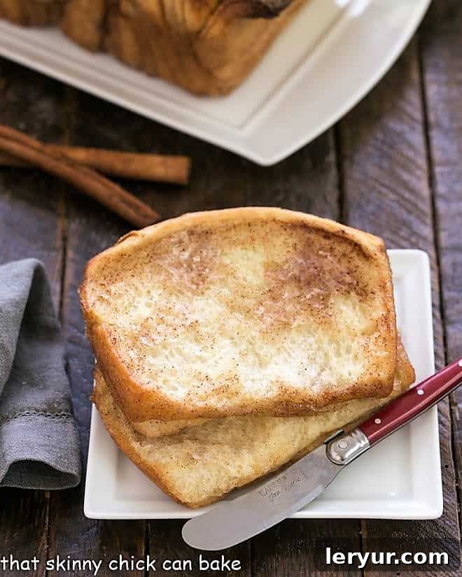Cinnamon Pull Apart Bread - a fun yeast bread filled with cinnamon sugar. Cinnamon Pull Apart Bread slices on a square white plate with a small knife