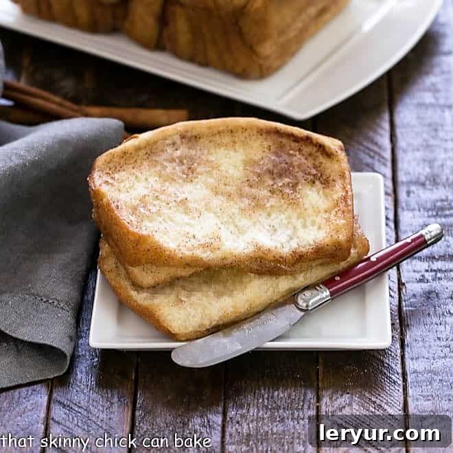 2 slices of cinnamon pull apart bread on a white plate with a red handle knife
