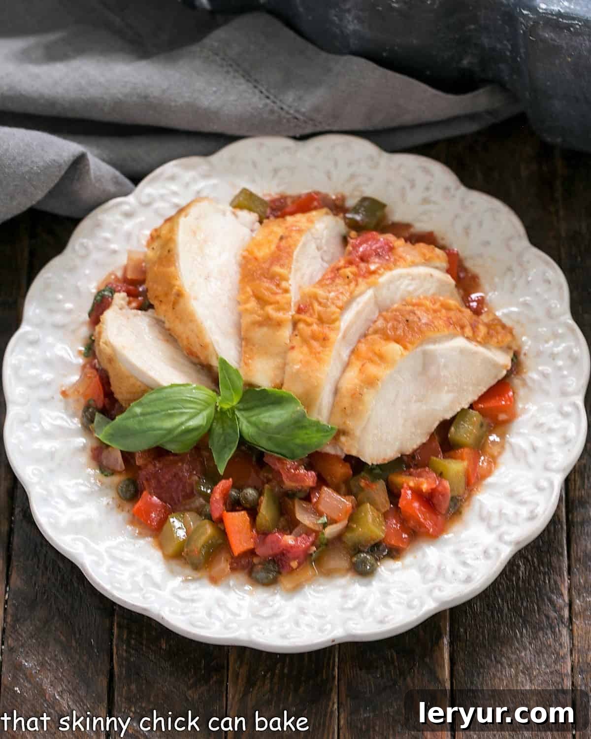 An inviting overhead view of Chicken Cacciatore artfully arranged on a decorative white plate, garnished with fresh basil. The rich, rustic sauce glistens under the light.
