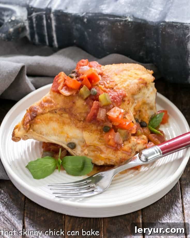 Chicken Cacciatore on a white plate with a red handle fork, showing a hearty portion of chicken and vegetables.