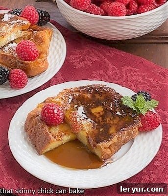 Candied French Toast 2 Sugar crusted slice of French Toast cut in half on a plate with syrup and berries, showing the soft interior.