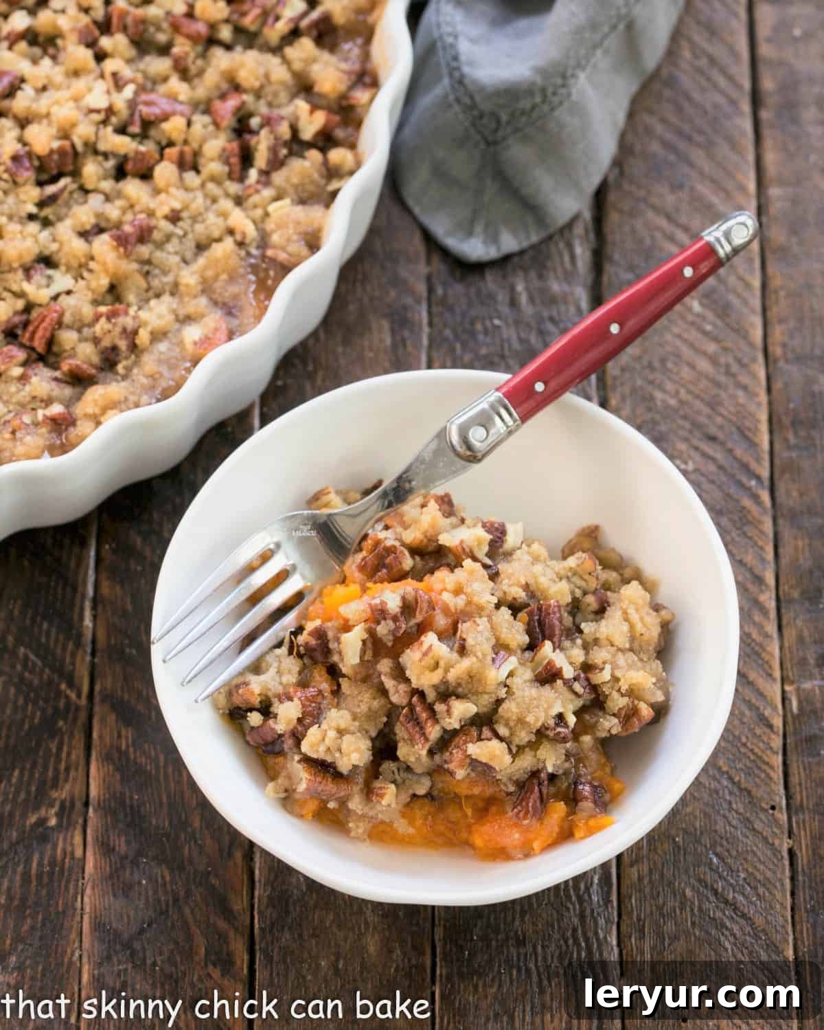 Small white bowl with easy sweet potato casserole and a red handle fork, highlighting the delicious texture.