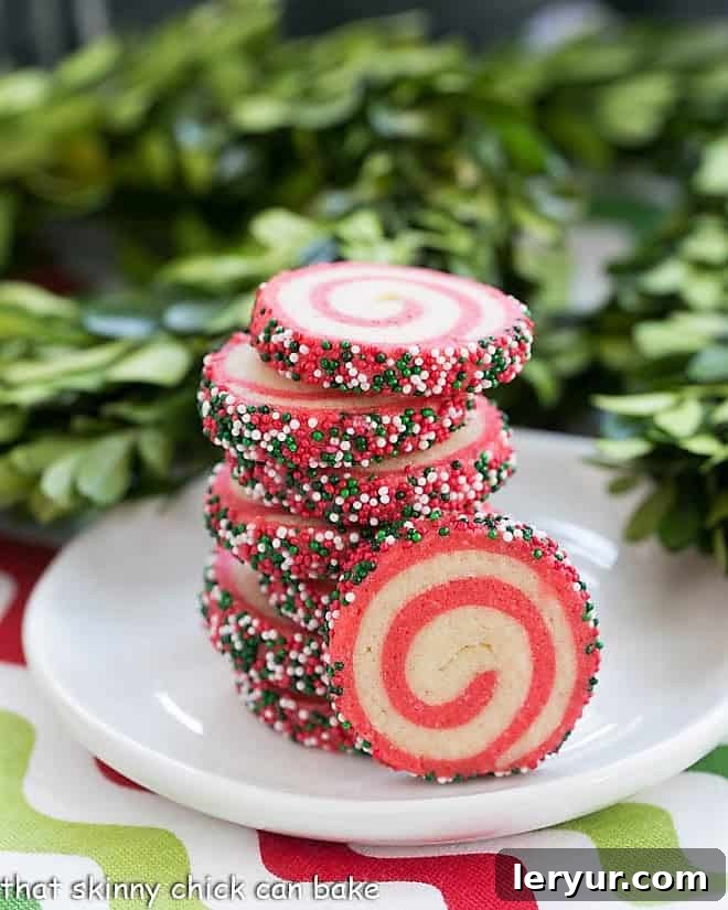 Holiday Pinwheel Cookies - Delicious, buttery and festive Christmas cookies that are adaptable to any holiday! A stack of vibrant red and green Holiday Pinwheel Cookies on a small white plate, showcasing their intricate spiral design.