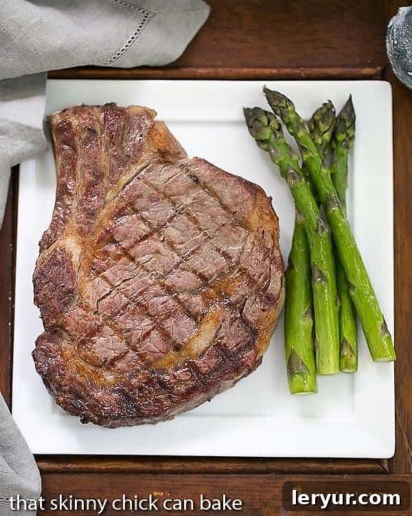 Perfectly seared rib eye steak on a dinner plate with crisp asparagus spears.