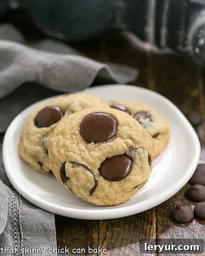 Southern Living's BEST Chocolate Chip Cookies - thick and chewy with loads of chocolate! Three perfectly baked Chewy Chocolate Chunk Cookies, rich with melted chocolate, arranged on a pristine round white dessert plate.