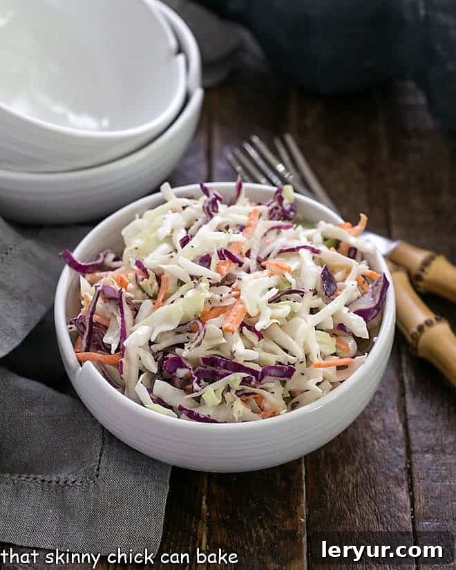 KFC coleslaw recipe in a white bowl with two spare bowls in the background, ready for serving.