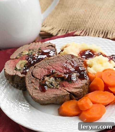 Gorgonzola and Mushroom Stuffed Beef Tenderloin - An elegant, celebratory entree you can make at home! Gorgonzola and Mushroom Stuffed Beef Tenderloin sliced on a white dinner plate, garnished with fresh herbs.