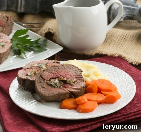 Gorgonzola and Mushroom Stuffed Beef Tenderloin - An elegant, celebratory entree you can make at home! Gorgonzola and Mushroom Stuffed Beef Tenderloin plated with roasted carrots and creamy mashed potatoes, ready to be served.