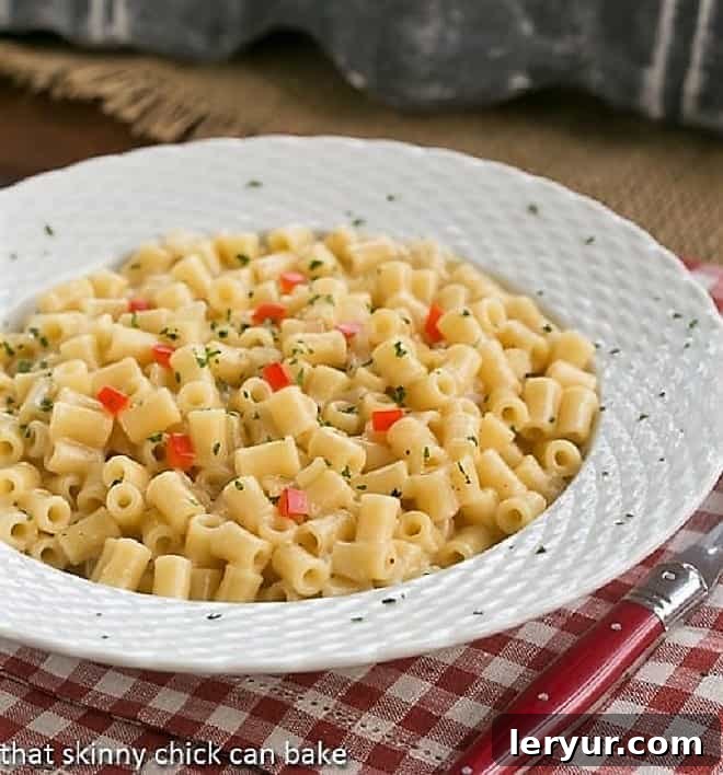 A delectable bowl of pasta risotto, served with a striking red-handled fork, resting on a cheerful checkered napkin. The close-up view highlights the inviting creaminess and perfect consistency of the dish.