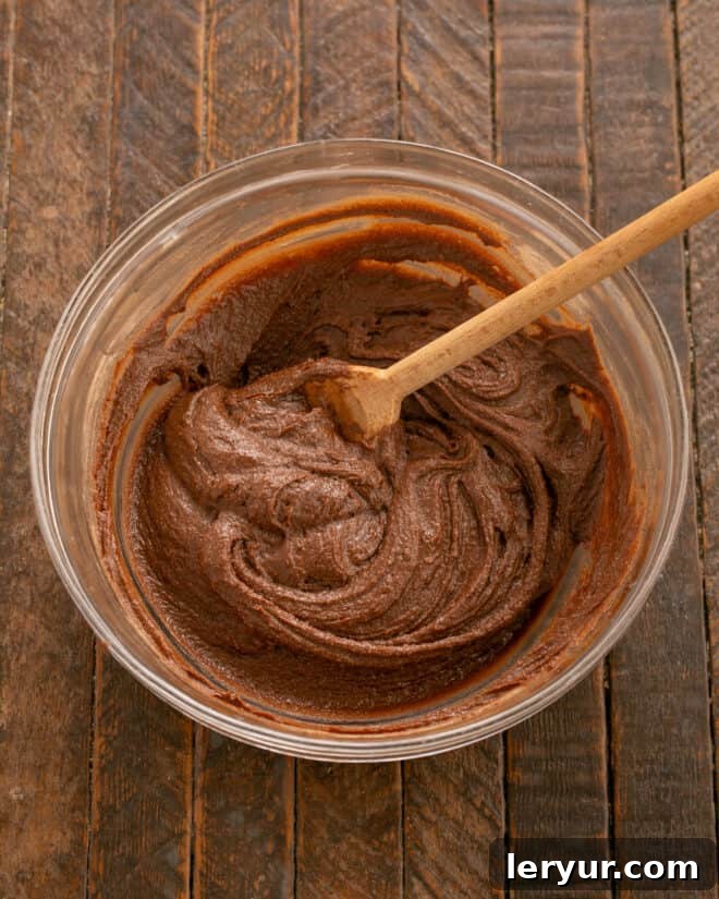 The dry flour and cocoa mixture being added to the wet butter, sugar, and egg mixture for the fudge cake.
