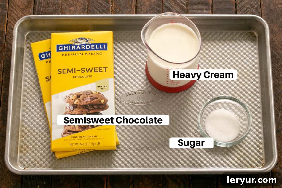 A selection of all frosting ingredients, including chocolate and heavy cream, presented with labels on a sleek metal sheet pan.