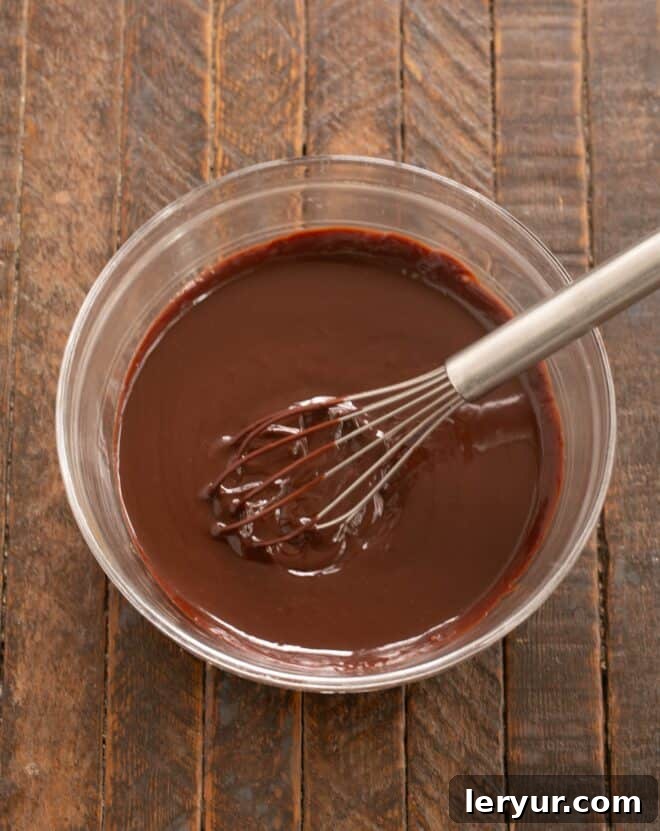 Step-by-step image showing how to make the ganache for the fudge cake, with melted chocolate and cream being whisked.