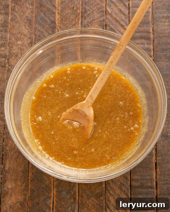 Eggs and vanilla extract being added to the butter and sugar mixture for the fudge cake.