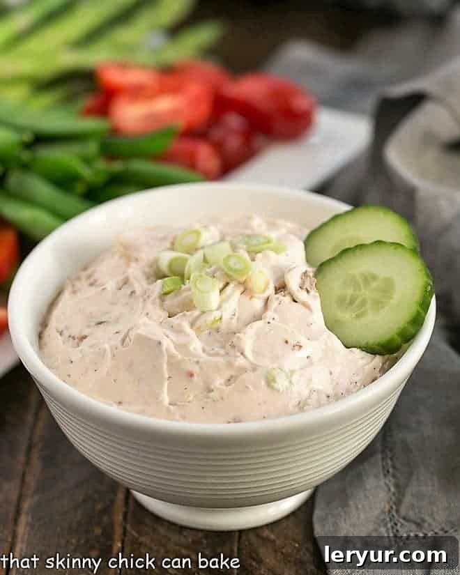 Inas Zesty Sun Dried Tomato Dip 2 A large white bowl of Sun-Dried Tomato Dip artfully arranged with a platter of fresh, colorful vegetables for dipping.