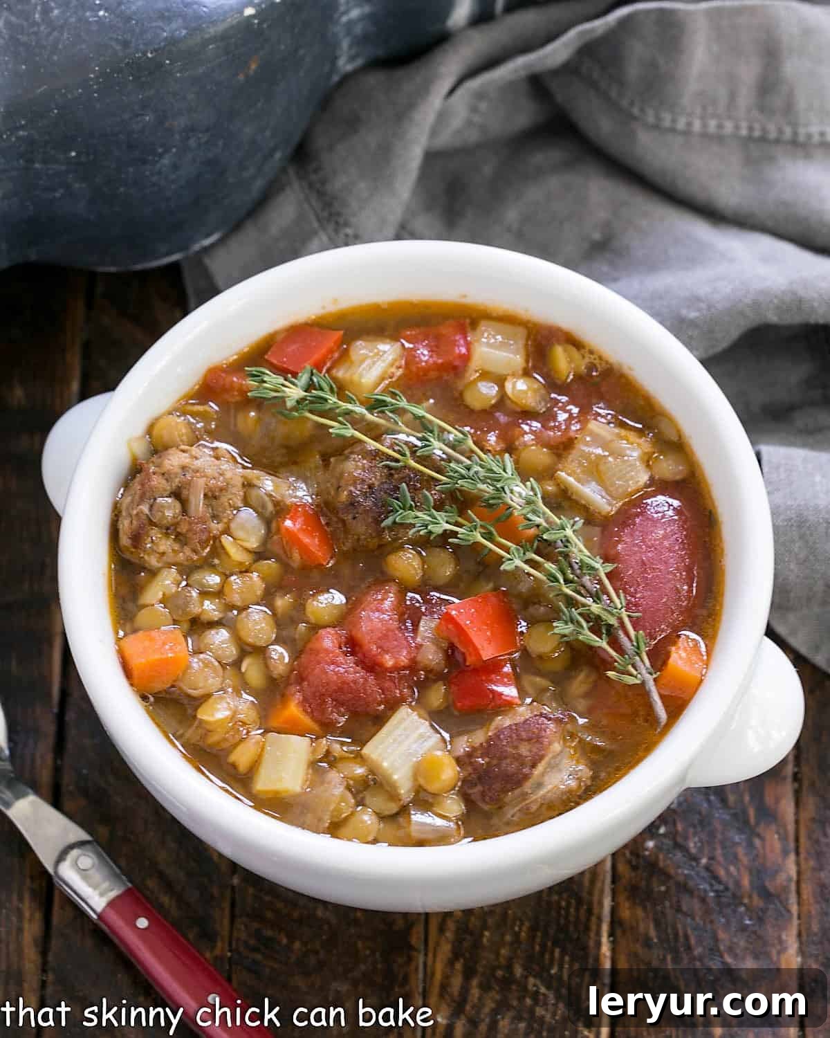 Hearty Sausage and Lentil Stew 2 Overhead view of a steaming white bowl of Sausage Lentil Soup garnished with fresh thyme leaves, ready to be served.