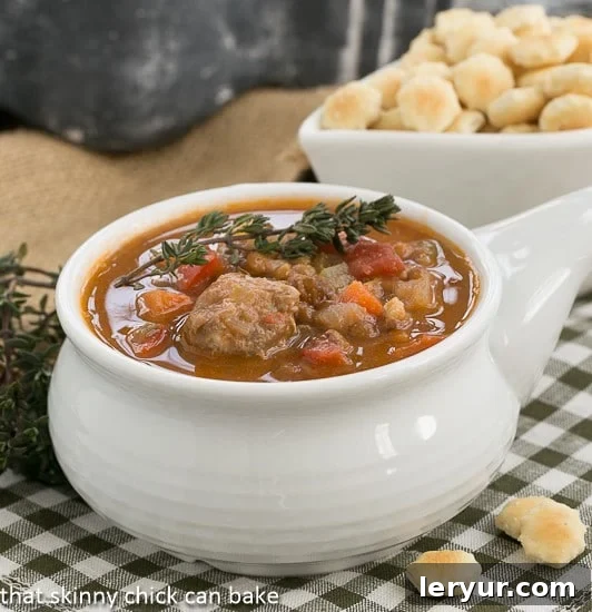 Lentil Soup with sausage: a hearty soup that will hit the spot on a chilly winter's night Close-up of a white soup bowl filled with hearty Sausage, Lentil and Vegetable Chowder, garnished and steaming, ready to be enjoyed.