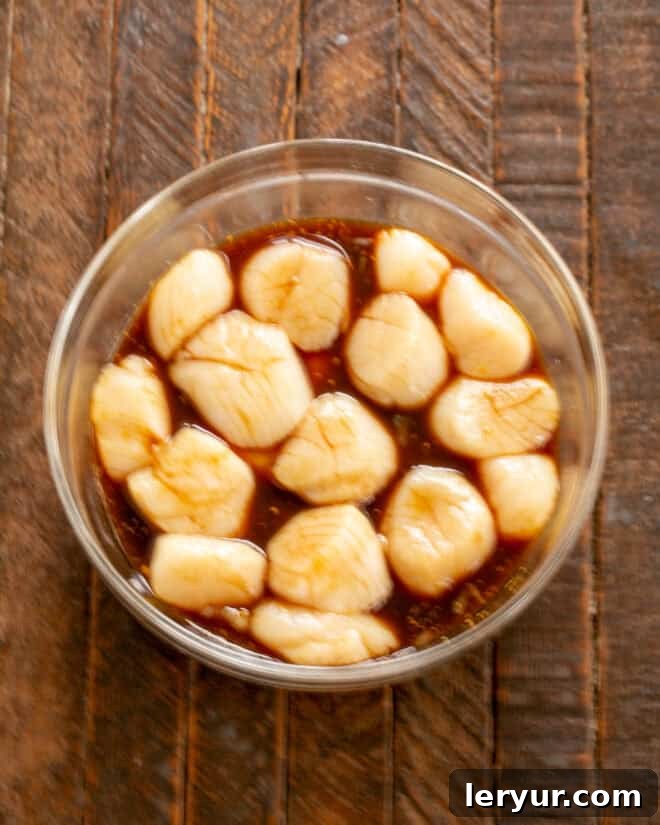 Maple Glazed Bacon Wrapped Scallops 5 Raw sea scallops soaking in a bowl of maple soy marinade.