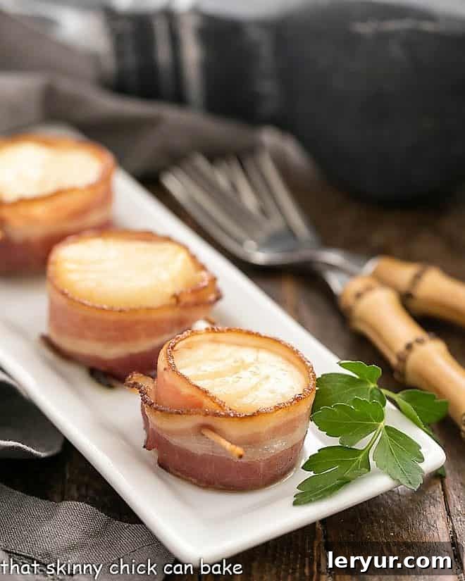 Maple Glazed Bacon Wrapped Scallops 7 Bacon-wrapped scallops arranged on a white baking tray, ready for the oven.