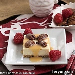 A perfectly portioned slice of caramel pecan cheesecake bar, showcasing its distinct layers of crust, creamy cheesecake, and a luscious topping of caramel and pecans.