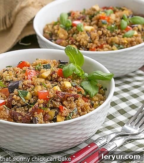 Two white bowls brimming with Quinoa Salad with Roasted Vegetables, garnished with fresh herbs, ready to be served as a healthy, satisfying meal