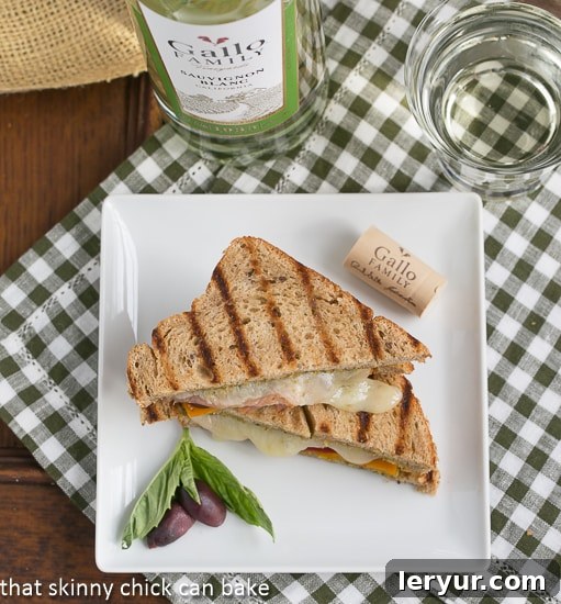 Close-up of a Mediterranean Grilled Cheese sandwich, showcasing its golden-brown crust and tempting filling of melted cheese, thin slices of prosciutto, and colorful vegetables