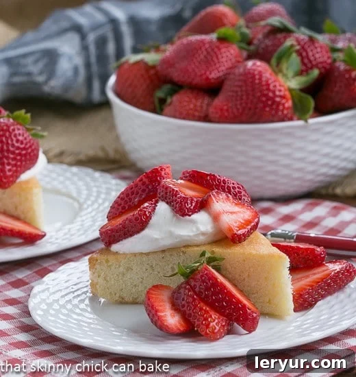 An elegant French Vanilla Sponge Cake, perfect as a sophisticated base for berry shortcakes Slice of French Visitandine Cake on a white plate topped with fresh berries and whipped cream, ready to be enjoyed