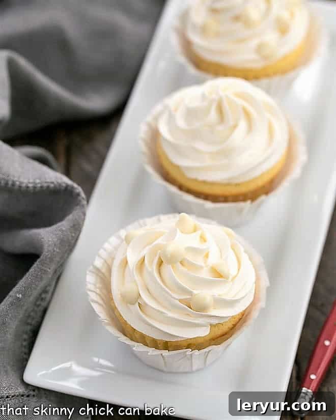 Ghirardelli Vanilla Cupcakes with White Chocolate Buttercream - tender vanilla cupcakes with a luscious swirl of Swiss meringue buttercream flavored with white chocolate! Vanilla Cupcakes with White Chocolate Buttercream on a rectangular ceramic tray.