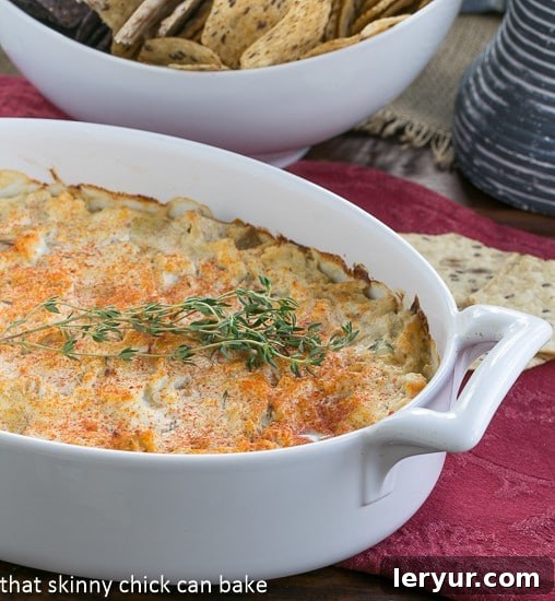 Hot Artichoke Shrimp Dip - A creamy shrimp artichoke appetizer that will be a hit at your next party! Hot Artichoke Shrimp Dip in an oval casserole dish, bubbling and golden brown from the oven.