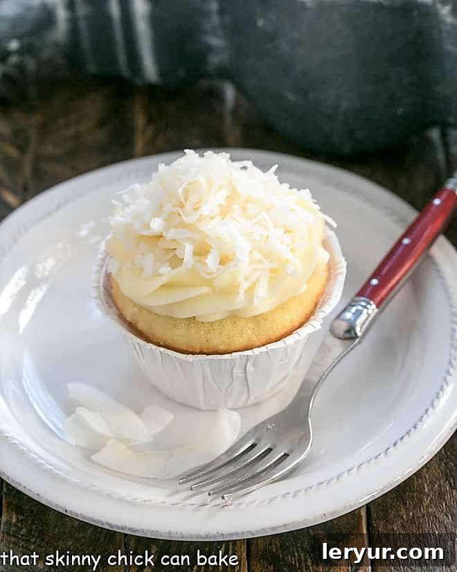 Close-up of a single Coconut Cupcake with Cream Cheese Frosting on a small white plate.