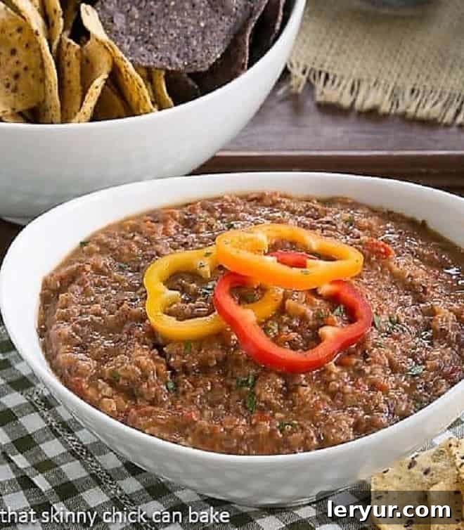 Smoky Black Bean Dip - A flavorful bean dip flavored with chipotles and more that's marvelous with tortilla chips! Rich and creamy Smoky Black Bean Dip served elegantly in a white ceramic bowl, garnished with fresh cilantro and a sprinkle of chili flakes. Perfect for dipping!