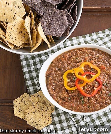 Smoky Black Bean Dip - A flavorful bean dip flavored with chipotles and more that's marvelous with tortilla chips! A close-up of Smoky Black Bean Dip in a white serving bowl, accompanied by a separate bowl overflowing with crunchy tortilla chips, ready for a party.