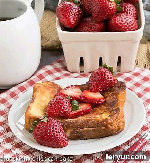 Strawberry Mascarpone Stuffed French Toast - An elegant, easy-to-make brunch entree! Strawberry Mascarpone Stuffed French Toast on a white plate topped with fresh strawberries and powdered sugar.