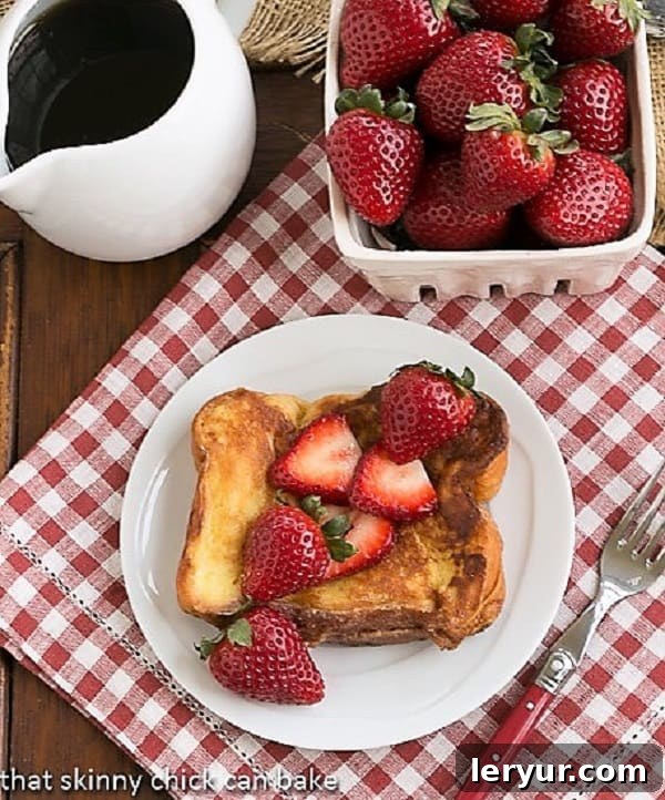 Strawberry Mascarpone Stuffed French Toast - a delicious twist on the classic French toast recipe with a filling of luscious mascarpone and sweet berries! Overhead view of Strawberry Mascarpone Stuffed French Toast with maple syrup and a basket of fresh strawberries.
