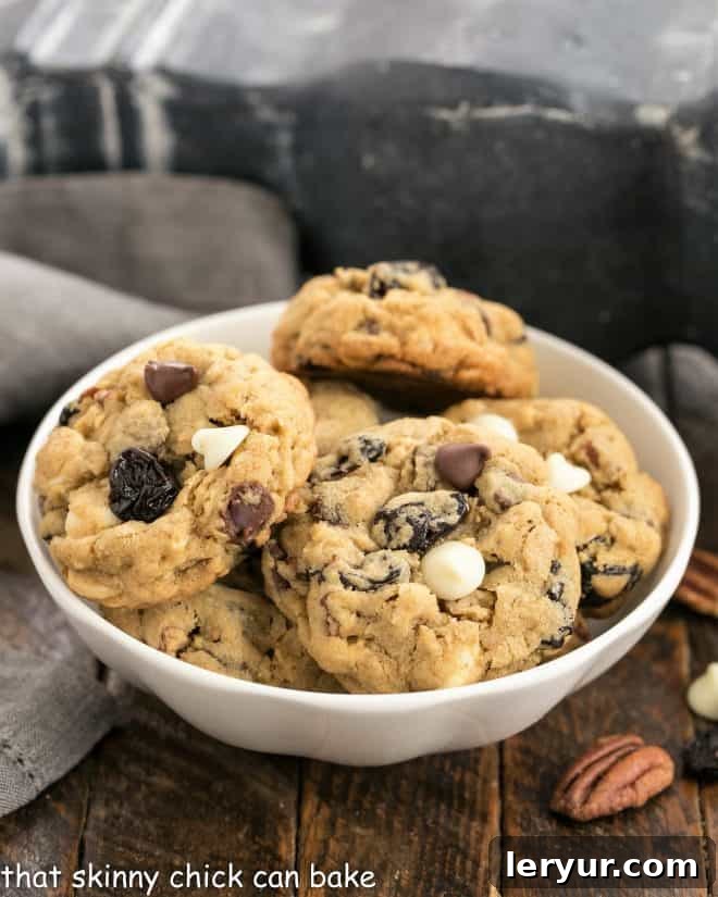 Oatmeal Cherry Chocolate Chip Cookies - Soft chewy and loaded with both semi-sweet and white chocolate chips along with dried cherries for an exquisite taste experience with every delicious bite! Oatmeal, Cherry and Chocolate Chip Cookies in a small white ceramic bowl